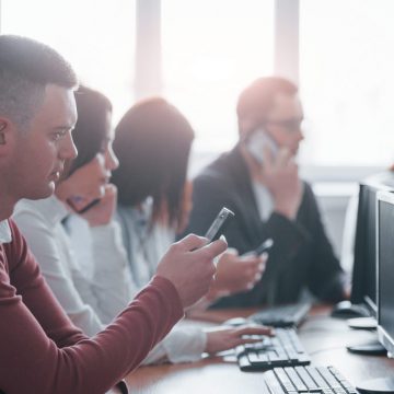 Black colored smartphone. Young people working in the call center. New deals is coming