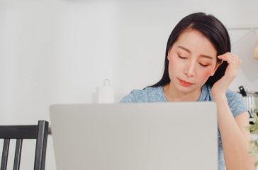 Young Asian business woman records of income and expenses at hom